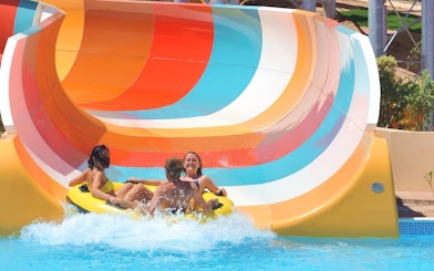 People enjoying a colorful water slide ride at Makadi Water World, Hurghada.