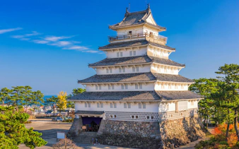 Shimabara Castle in Japan with traditional architecture and surrounding greenery.