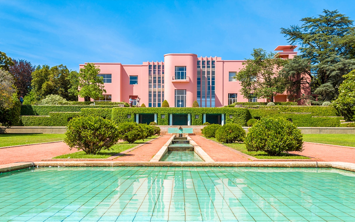 Serralves gardens with pink Art Deco building and green hedges in Porto, Portugal.