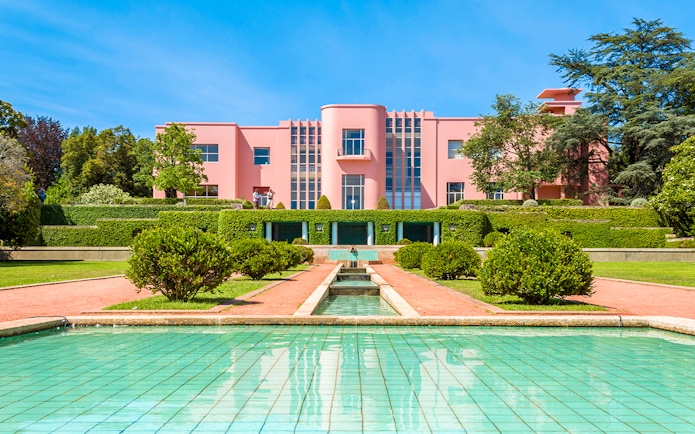 Serralves gardens with pink Art Deco building and green hedges in Porto, Portugal.