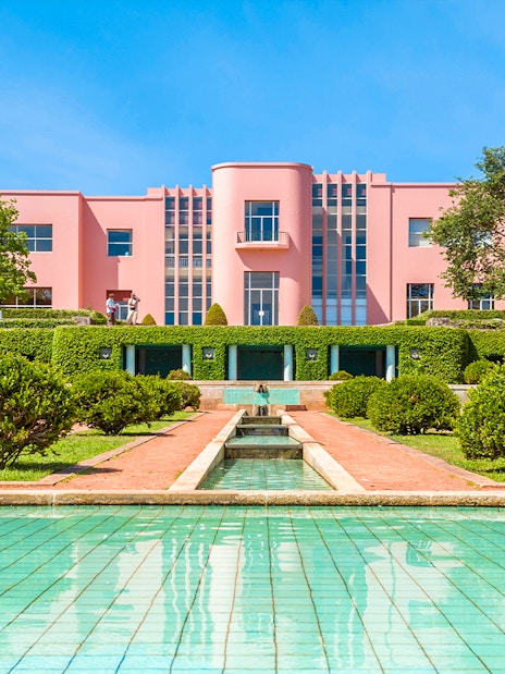 Serralves gardens with pink Art Deco building and green hedges in Porto, Portugal.