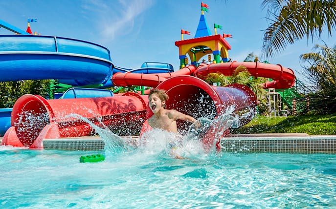 Child splashing in water at Gardaland's Legoland Jungle Adventures, Verona.