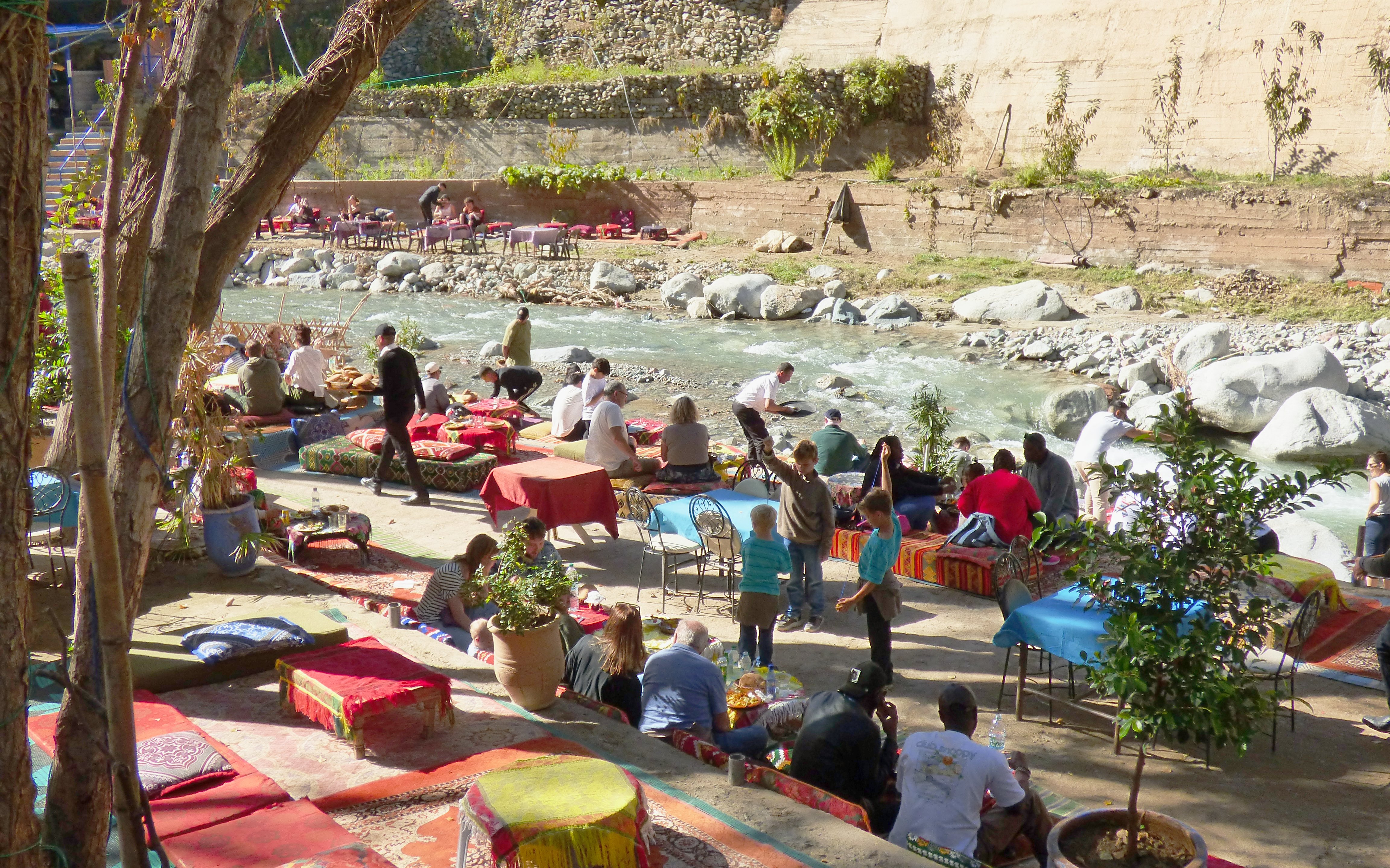 Tourists dining by a river in Ourika Valley, Morocco.