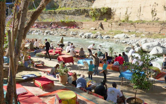 Tourists dining by a river in Ourika Valley, Morocco.