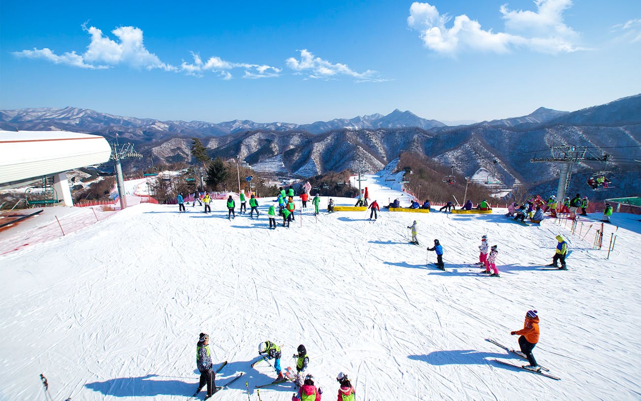 Skiers enjoying slopes at Elysian Gangchon Ski Resort with mountain views, near Seoul.