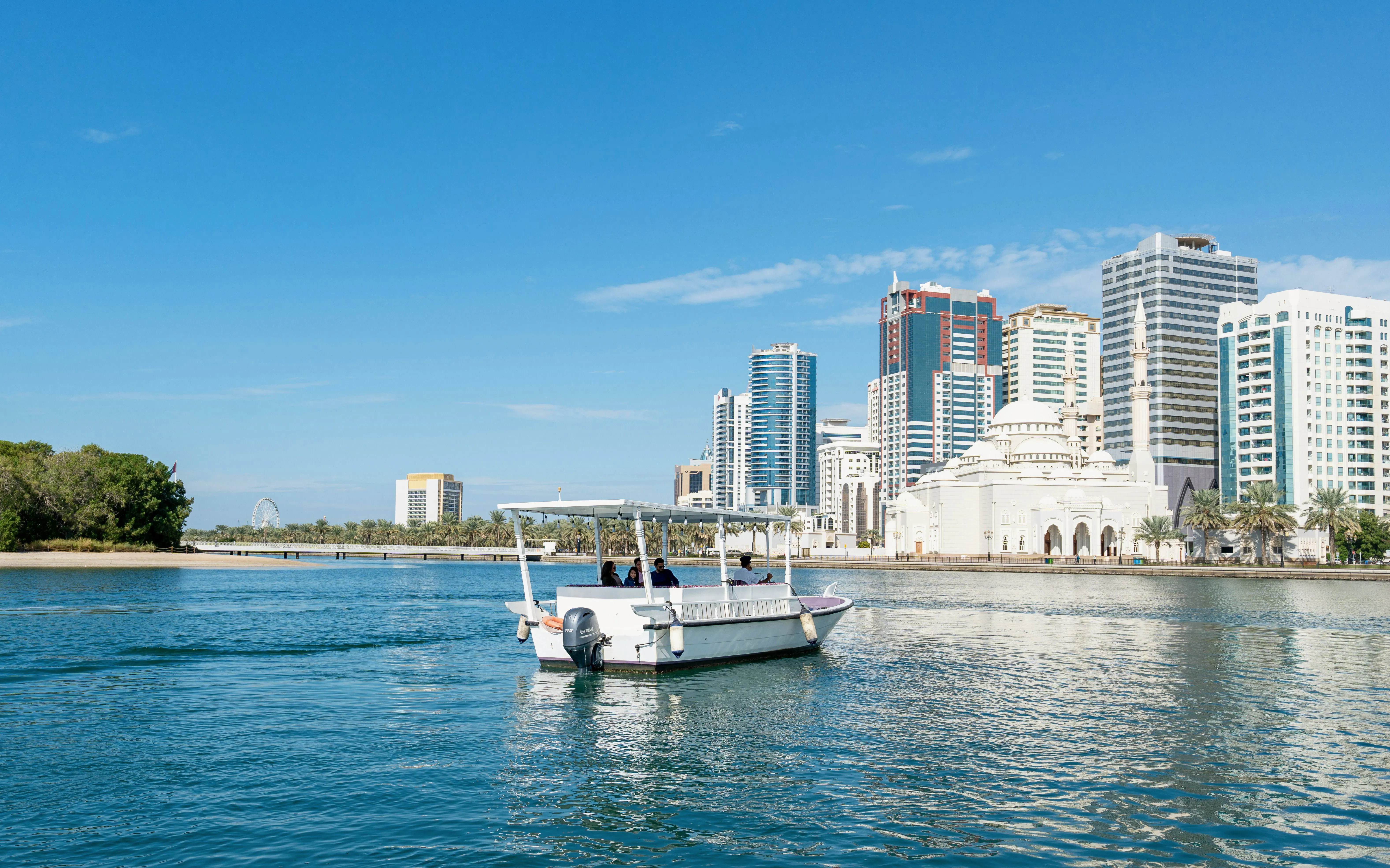 Boat tour on Khalid Lagoon with Sharjah skyline in the background.