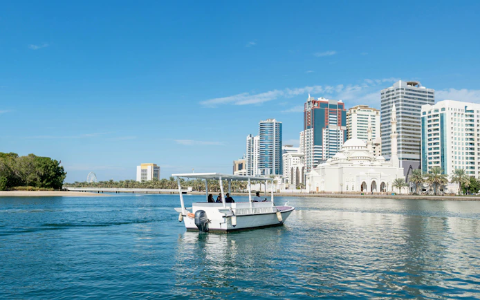 Boat tour on Khalid Lagoon with Sharjah skyline in the background.