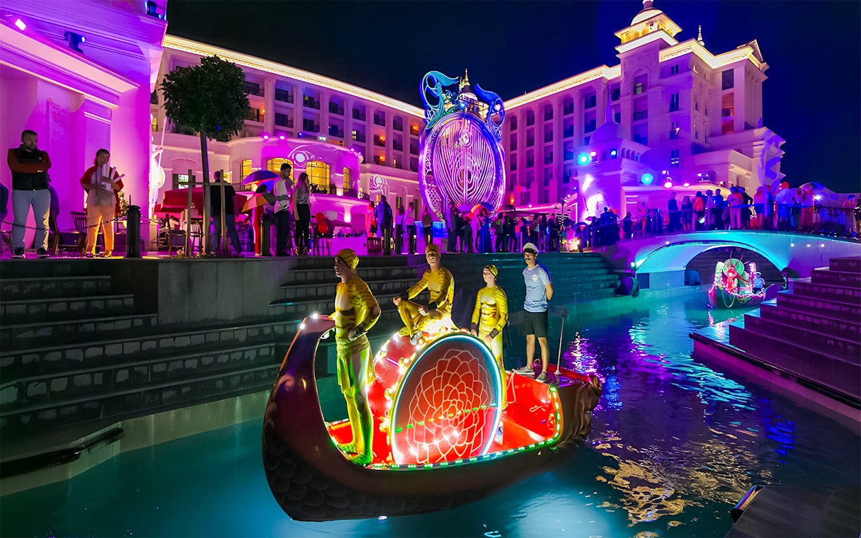 Boat parade at Land of Legends Night Show with illuminated performers and vibrant lights.