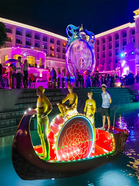 Boat parade at Land of Legends Night Show with illuminated performers and vibrant lights.