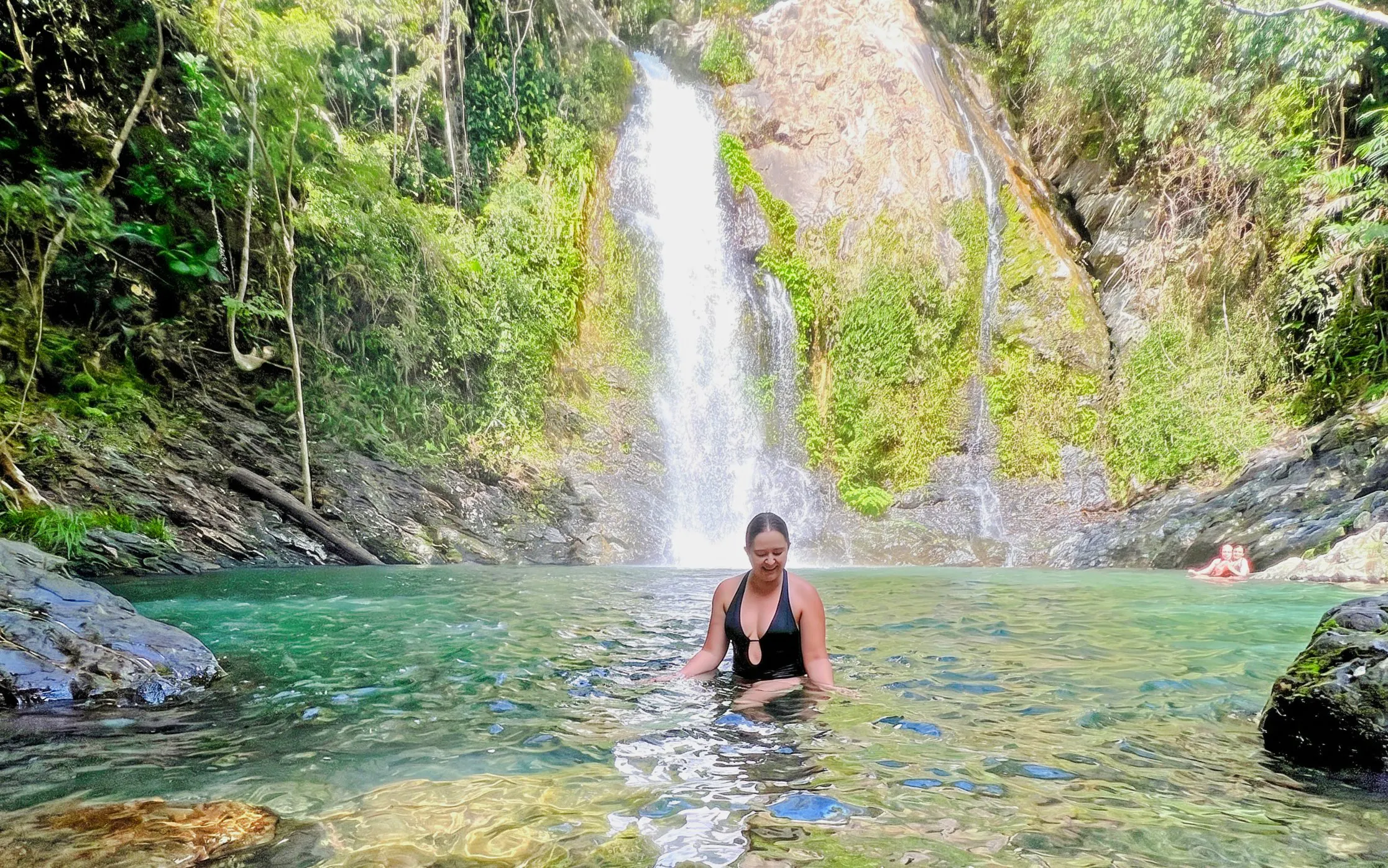 Woman swimming near waterfall at Daintree Rainforest, Cassowary Falls Tour.
