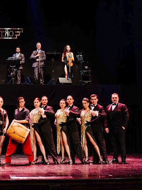 Performers on stage at Tango Porteño Show in Buenos Aires, featuring dancers and musicians.