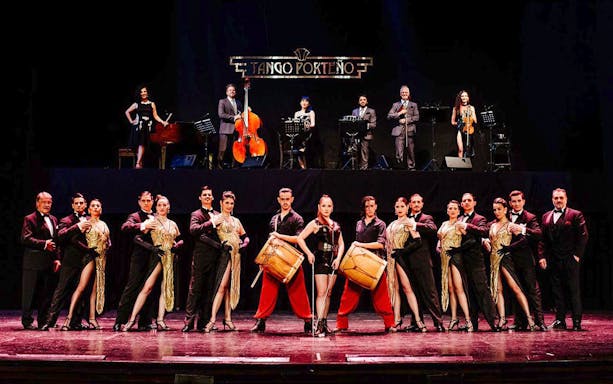 Performers on stage at Tango Porteño Show in Buenos Aires, featuring dancers and musicians.