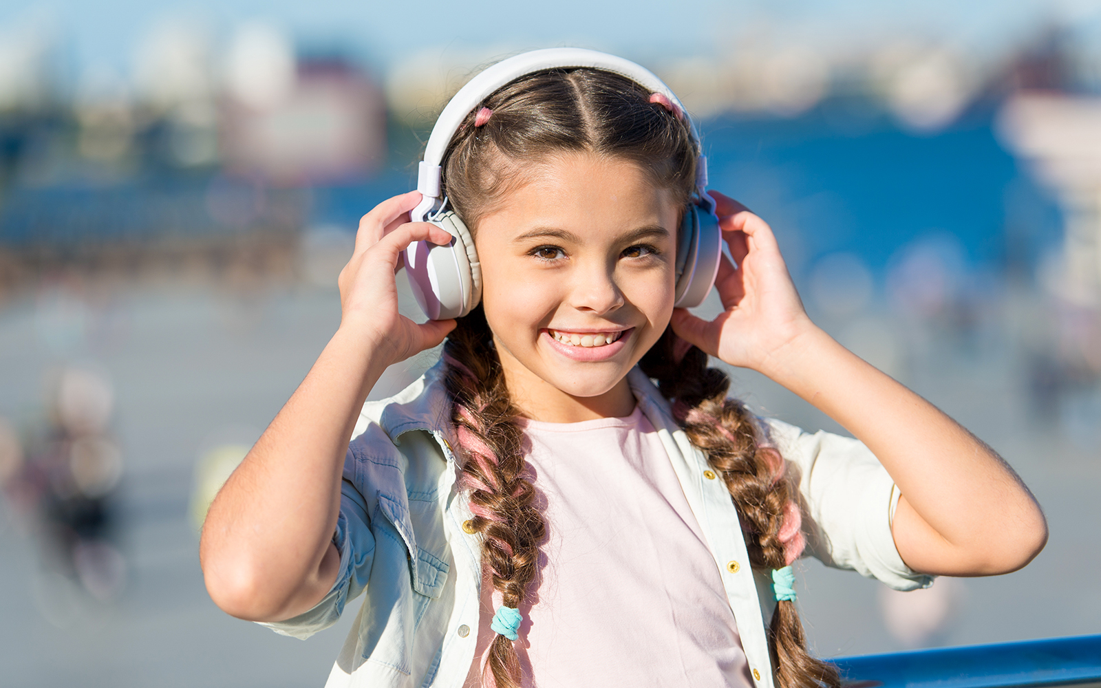 Ein lächelndes Mädchen mit zwei Zöpfen und großen Kopfhörern