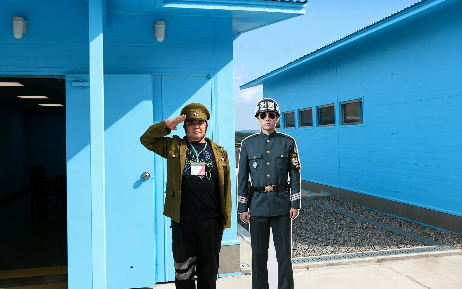 Person saluting beside a soldier cutout at DMZ JSA Photo Zone, South Korea.