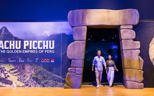 Visitors entering Machu Picchu exhibit with multimedia displays in Peru.