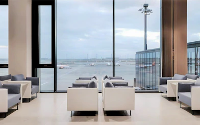 Seating area in BER Lounge Tempelhof at Berlin Brandenburg Airport with runway view.