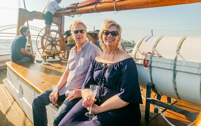 Couple enjoying a Tall Ship Cruise on Sydney Harbour with the Harbour Bridge in the background.