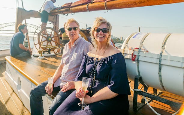 Couple enjoying a Tall Ship Cruise on Sydney Harbour with the Harbour Bridge in the background.