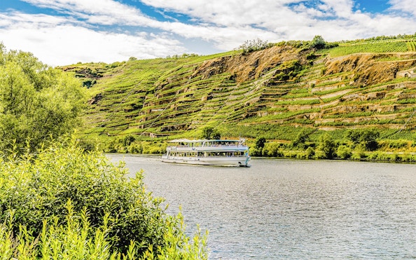 Cruise boat on the Moselle River with terraced vineyards in Koblenz.