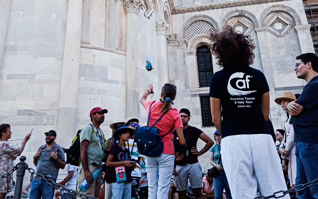 Tour group in Pisa with guide near cathedral, part of Florence to Pisa tour.