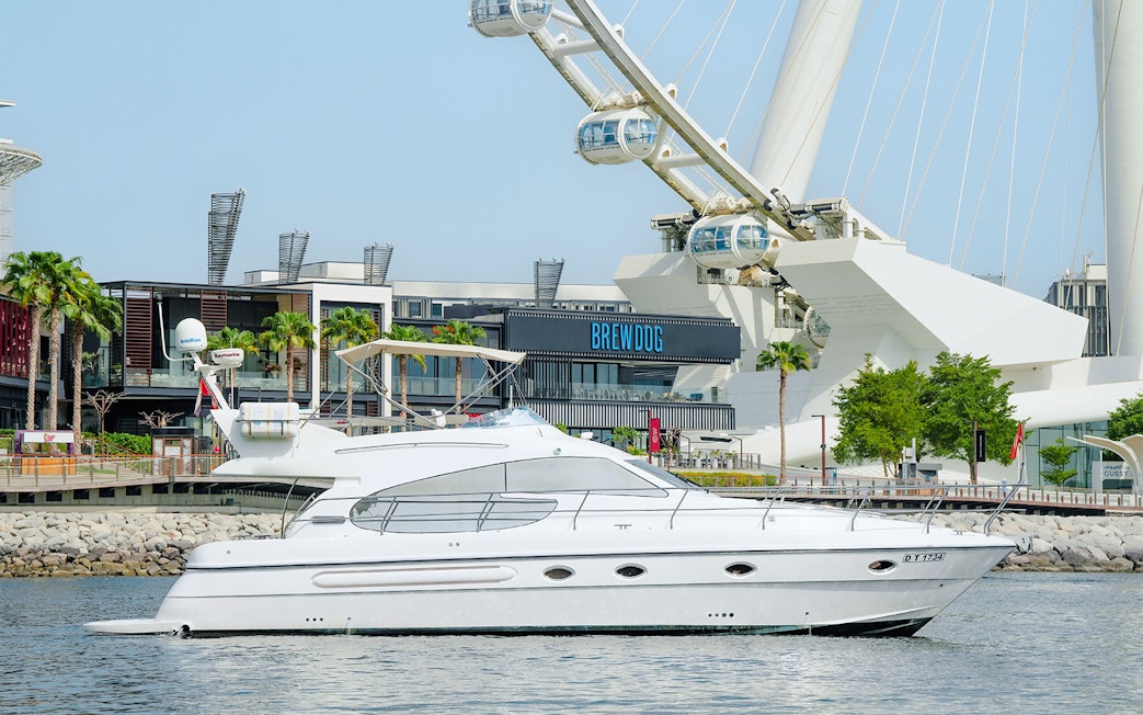 Luxury yacht cruising with Ain Dubai Ferris wheel in the background.