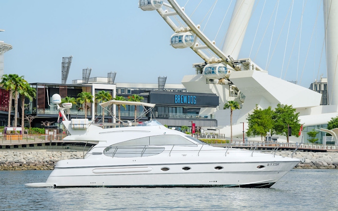 Luxury yacht cruising with Ain Dubai Ferris wheel in the background.