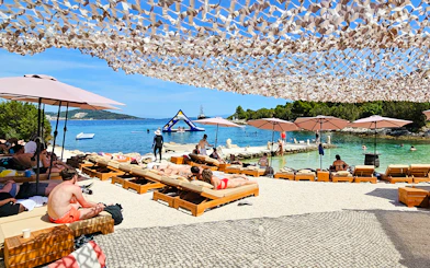 Sunbathers on loungers by the Blue Lagoon, Croatia, with inflatable water park in the background.