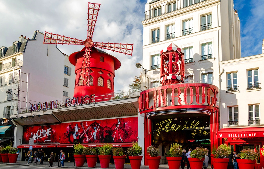 Moulin Rouge entrance with iconic red windmill in Paris, France.