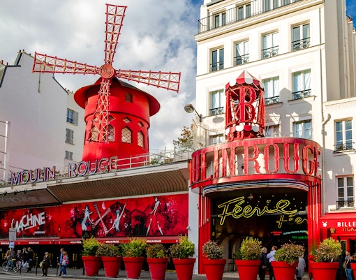 Moulin Rouge in Paris with illuminated windmill and neon signs at night.