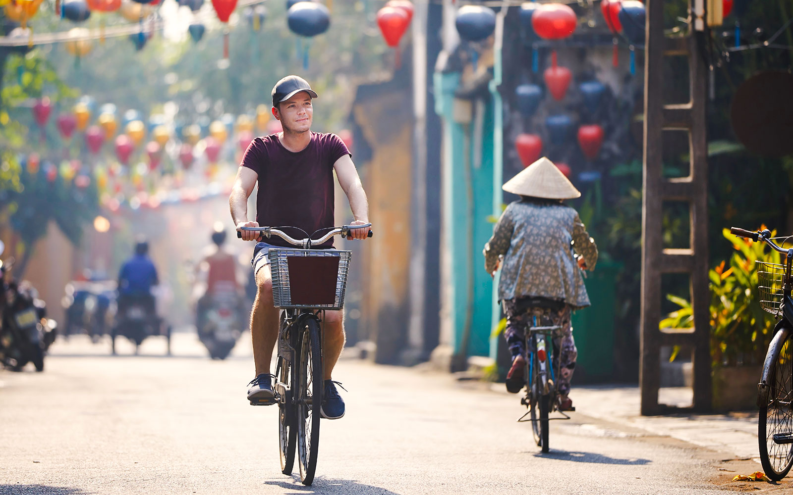 Tourist cycling through lantern-lined street in Hoi An, Vietnam.