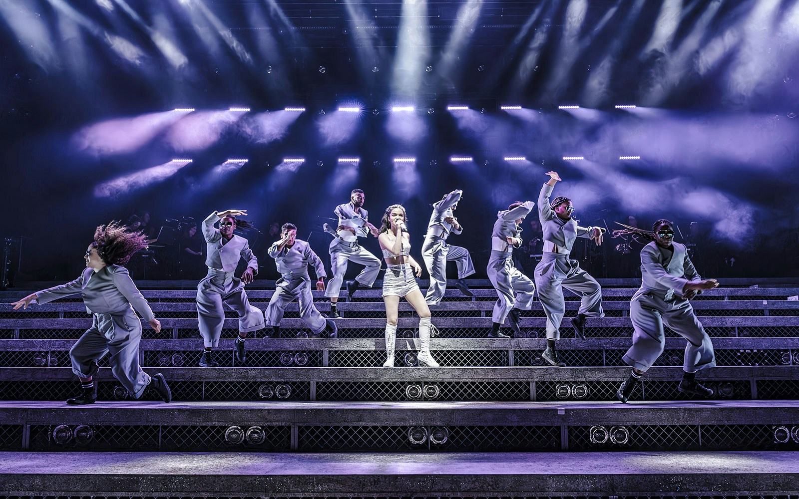 Performers dancing on stage during Evita musical with dramatic lighting.