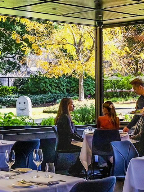 Visitors dining at Garden Restaurant, NGV International, Melbourne, with garden view.