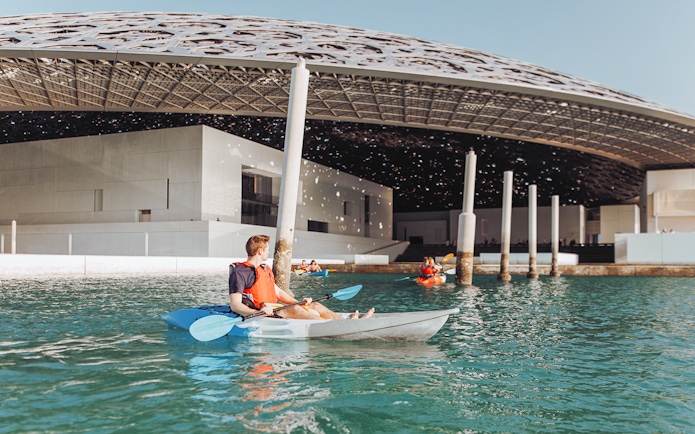 Kayakers paddling near Louvre Abu Dhabi's dome on a guided tour.