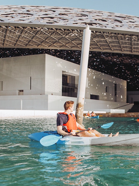 Kayakers paddling near Louvre Abu Dhabi's dome on a guided tour.