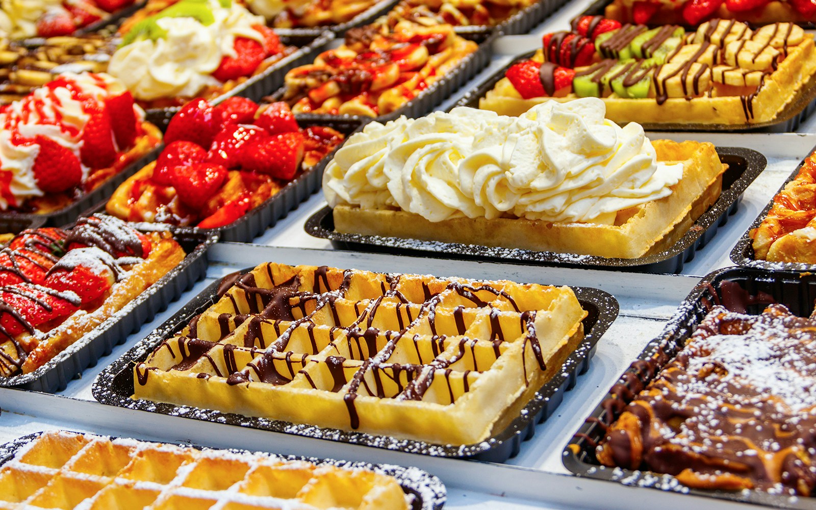 Belgian waffles topped with strawberries, cream, and chocolate on display.