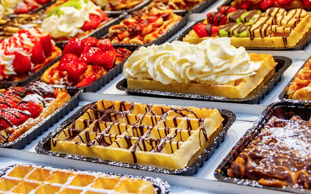 Belgian waffles topped with strawberries, cream, and chocolate on display.
