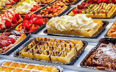 Belgian waffles topped with strawberries, cream, and chocolate on display.