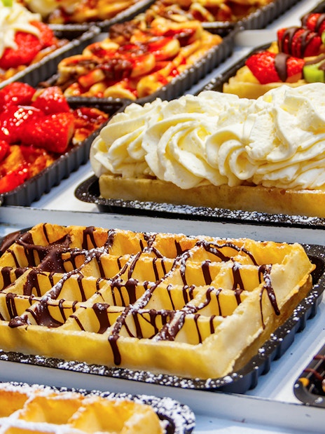 Belgian waffles topped with strawberries, cream, and chocolate on display.