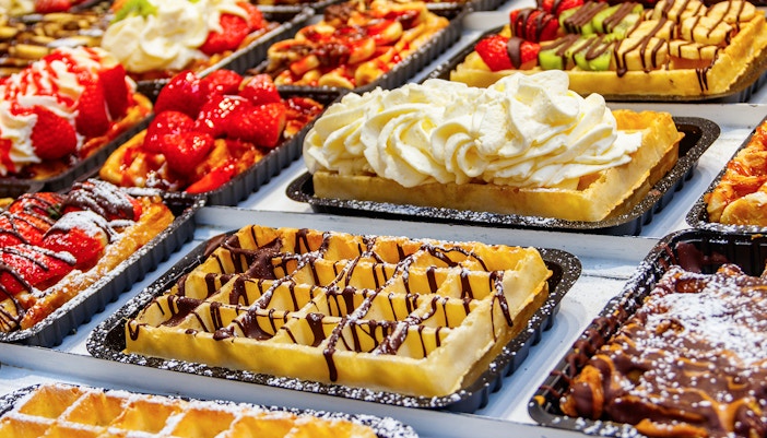 Belgian waffles topped with strawberries, cream, and chocolate on display.