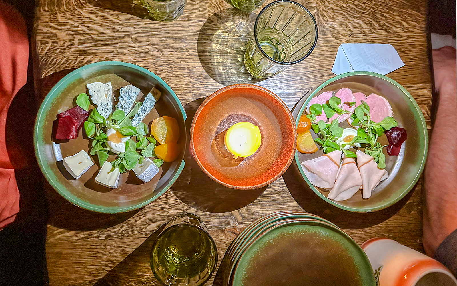 Medieval dinner table with assorted cheeses, meats, and a candle centerpiece.