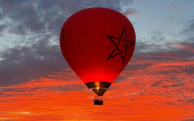 Hot air balloon over Marrakech at sunrise with vibrant sky.