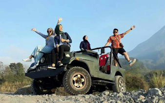 Tourists enjoying a Jeep ride on Merapi Lava Tour at sunrise, with mountain view.