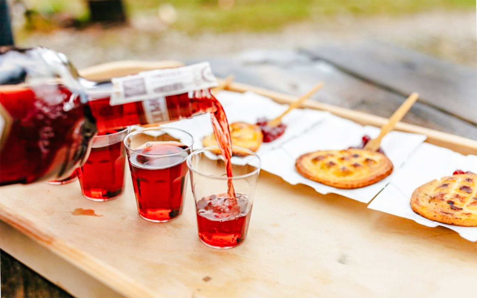 Pouring red drink into glasses with Oscypek cheese on sticks, Zakopane full-day trip.