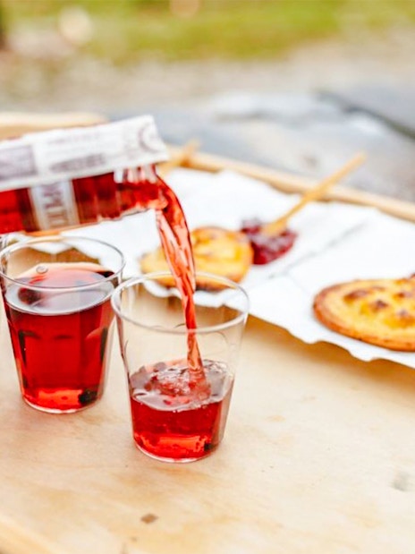 Pouring red drink into glasses with Oscypek cheese on sticks, Zakopane full-day trip.