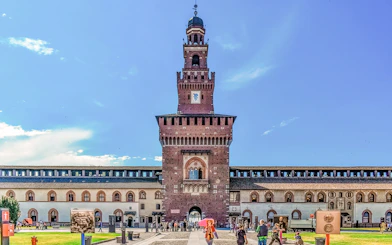Sforza Castle courtyard with central tower in Milan, Italy, visitors exploring the historic site.