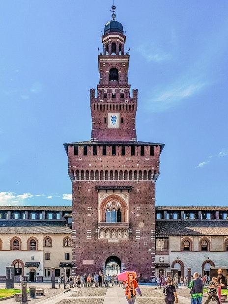 Sforza Castle courtyard with central tower in Milan, Italy, visitors exploring the historic site.