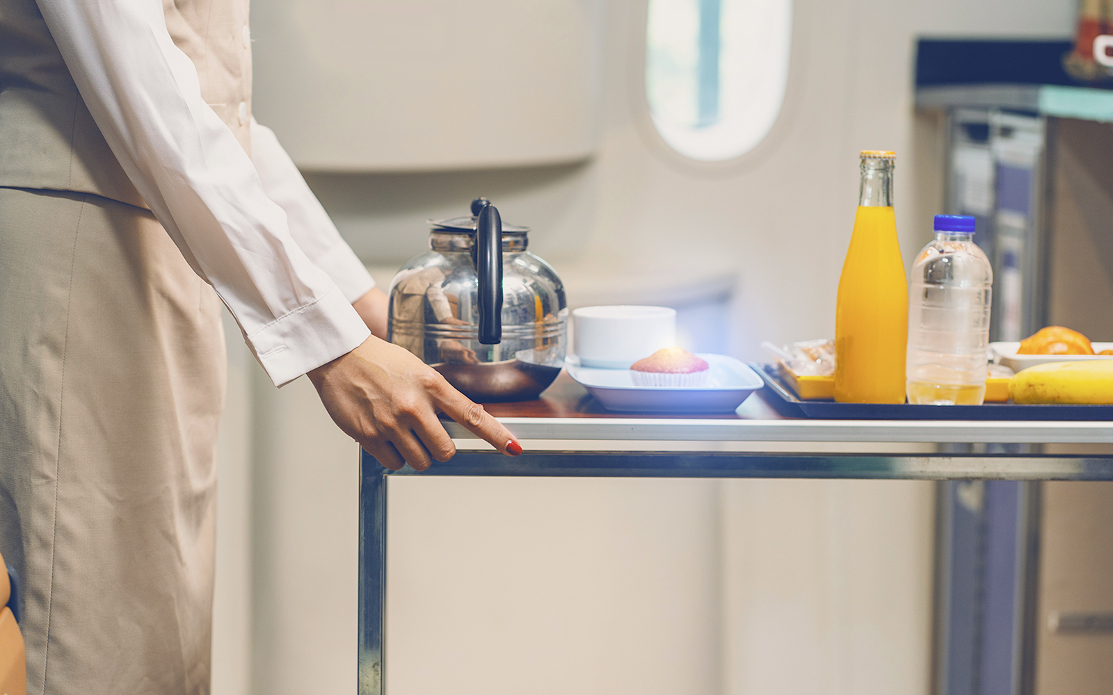 Female flight attendant wearing uniform pushing a car serving food, drinks, tea, coffee, water on the train