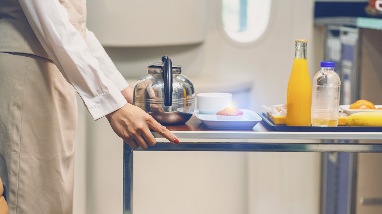 Female flight attendant wearing uniform pushing a car serving food, drinks, tea, coffee, water on the train