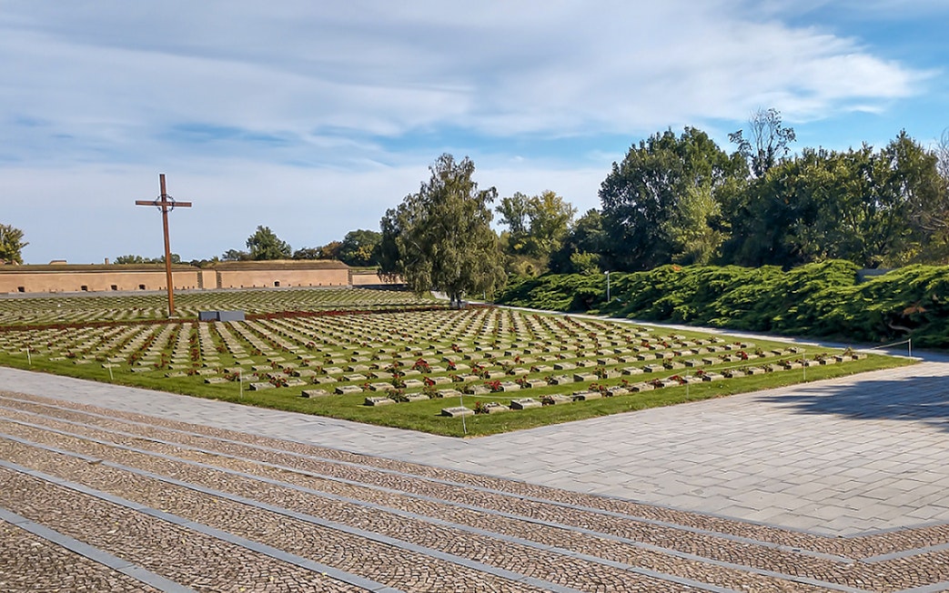 Terezin Concentration Camp cemetery with rows of graves and a large cross.