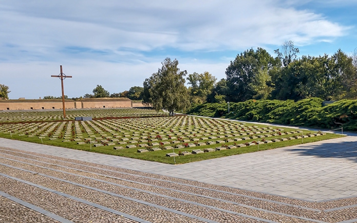 Terezin Concentration Camp cemetery with rows of graves and a large cross.